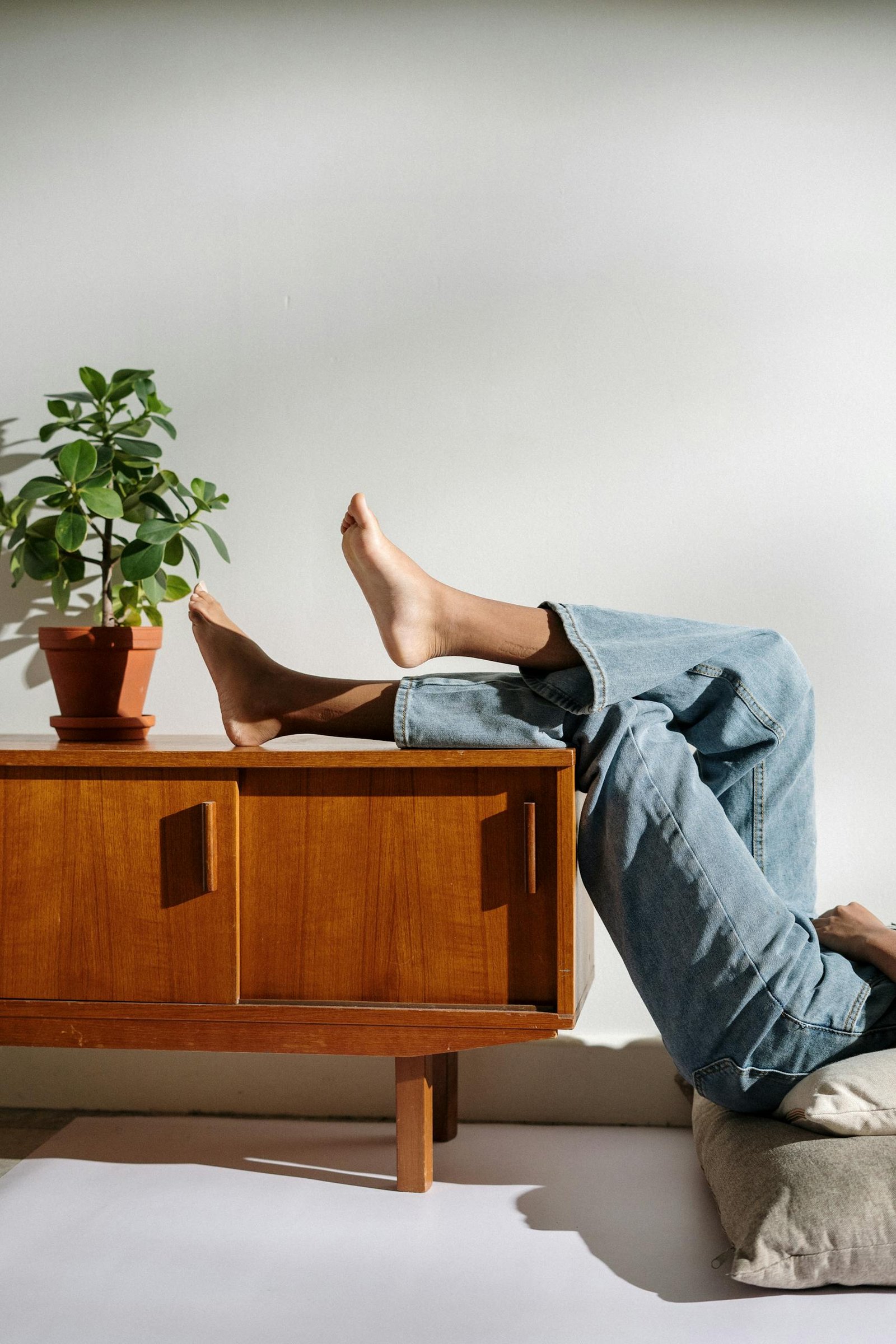 Casual lifestyle scene with bare feet and denim in a cozy interior.